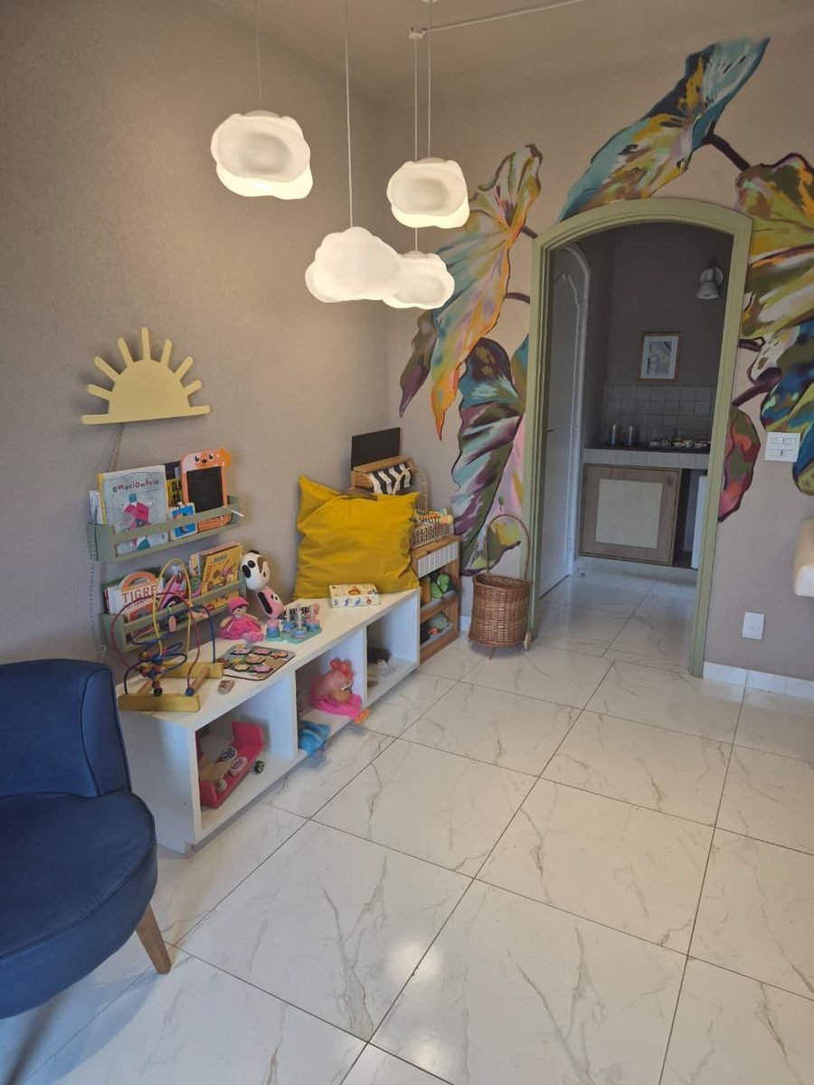Cantinho infantil do consultório com brinquedos, livros e luminárias em formato de nuvem