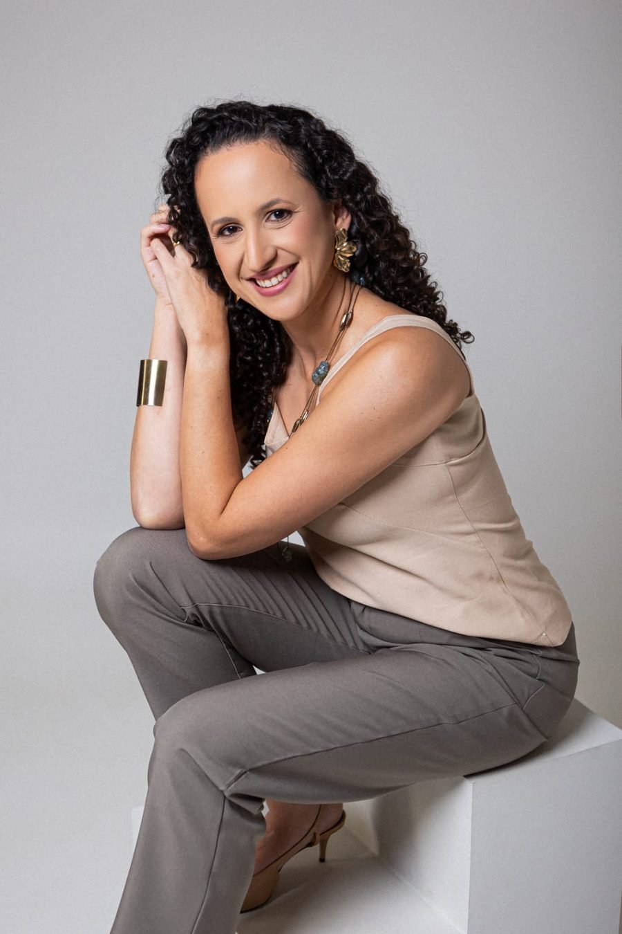 Dra. Rhayany sentada, sorrindo com a mão apoiada no rosto, em postura acolhedora